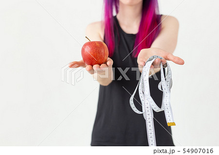 Young blurred asian girl hipster colored hair holding in hands a measuring tape and apple posing on 54907016