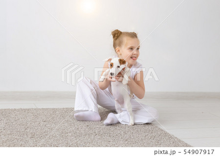 Dogs, pets and animal concept - Little child girl sitting with puppy Jack Russell Terrier Dogs, pets and animal concept - Little child girl sitting with puppy Jack Russell Terrier 54907917