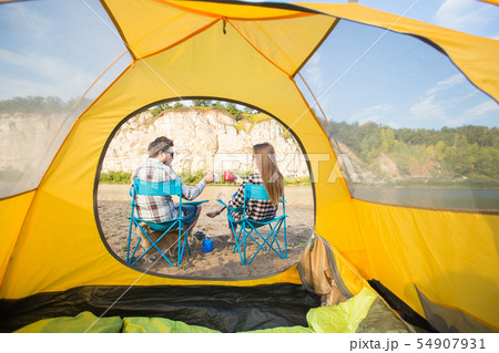 People, tourism and nature concept - Cute couple sitting with a cat near yellow tent 54907931