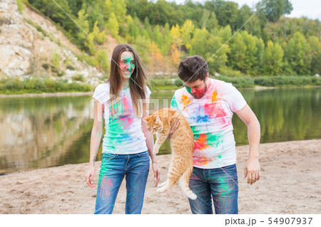 Festival holi, tourism and nature concept - Portrait of woman and man with cat covered multi-colored 54907937
