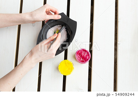 Color and hairdresser concept - female hairdresser in process of mixing hair dye color on the table Color and hairdresser concept - female hairdresser in process of mixing hair dye color on the table 54909244