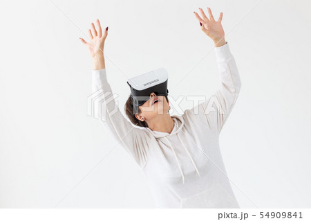 Unidentified middle-aged woman in a light sweater plays a 3D game with glasses of virtual reality on 54909841