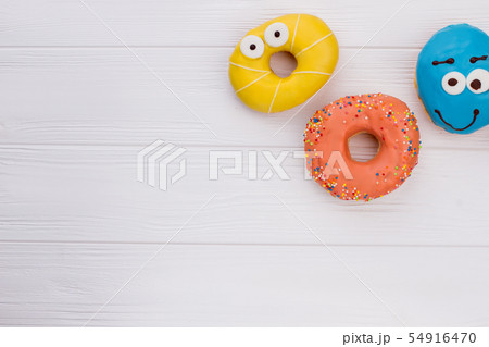 Donuts with funny eyes on wooden background. Donuts with funny eyes on wooden background. 54916470