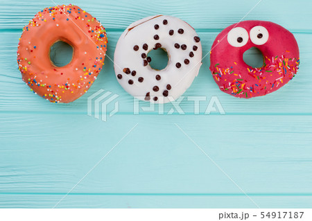 Three different donuts on blue wooden background. 54917187