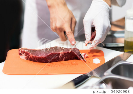 Chef cutting fresh raw meat with knife in the 54920908