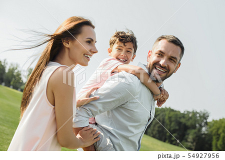 I love my parents Young and strong father carrying his happy son on shoulders while spending time I love my parents Young and strong father carrying his happy son on shoulders while spending time 54927956