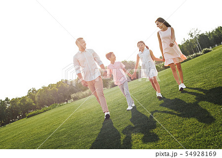 Spending weekend with family. Full length of happy and young family of four holding hands, smiling Spending weekend with family. Full length of happy and young family of four holding hands, smiling 54928169
