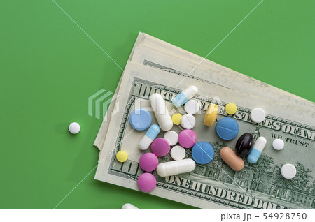 Different Multicolored Pills on One Hundred Dollar Bills Different Multicolored Pills on One Hundred Dollar Bills 54928750