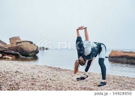 Warming up before training. Strong disabled athlete woman insportswear with prosthetic leg doing 54928950