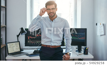 Successful trader. Modern young businessman in formal clothes adjusting his eyeglasses and looking Successful trader. Modern young businessman in formal clothes adjusting his eyeglasses and looking 54929258