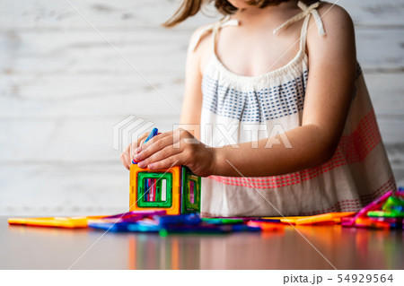 Portrait of beautiful thoughtful little girl playing colorful magnet plastic blocks kit, daydreaming Portrait of beautiful thoughtful little girl playing colorful magnet plastic blocks kit, daydreaming 54929564