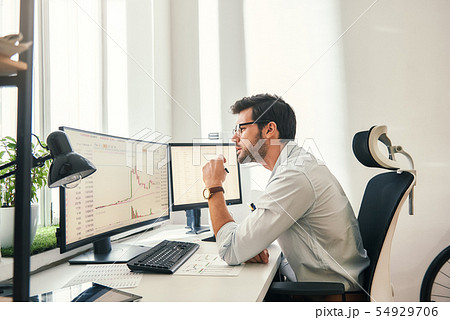 Busy working. Handsome bearded trader in formal wear and eyeglasses is analyzing trading charts and 54929706