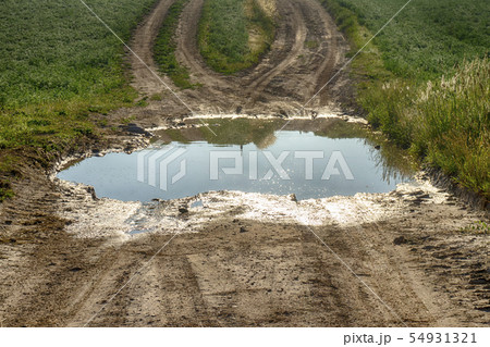 Large puddle of water on a gravel road Large puddle of water on a gravel road 54931321