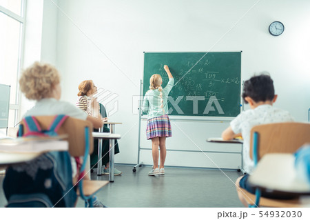School girl speaking and writing in front of the class. 54932030