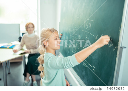 Happy girl doing sums near the school board. 54932032
