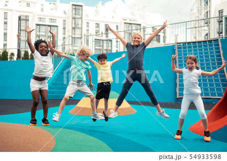 Cheerful pupils jumping up and down on a sports ground. Cheerful pupils jumping up and down on a sports ground. 54933598