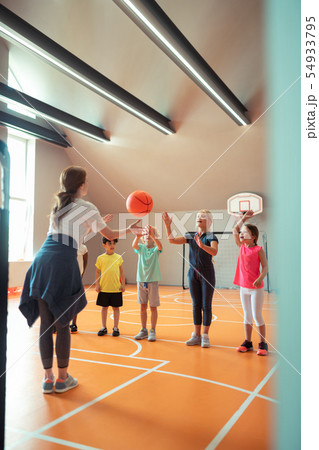 Sports teacher throwing ball to her pupils. Sports teacher throwing ball to her pupils. 54933795