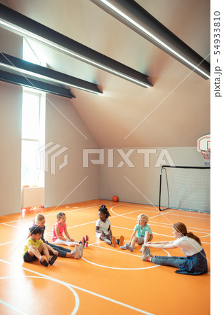 Young coach training her pupils in spacious gym. Young coach training her pupils in spacious gym. 54933810