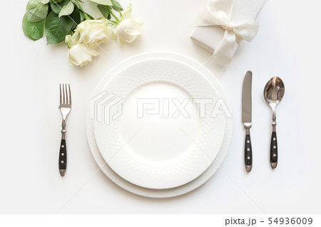 White table setting with rose, gift, dishware. White table setting with rose, gift, dishware. 54936009
