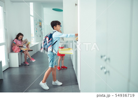Schoolboy wearing white sneakers opening school locker 54936719