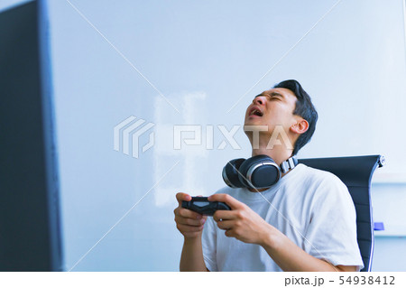 [eスポーツのイメージ] 対戦相手に完敗したプロゲーマーが失意の底に沈むシーンをイメージして撮影 54938412