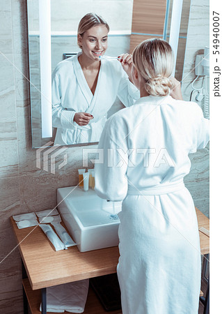 Beautiful lady with tied hair staying in front of the mirror Beautiful lady with tied hair staying in front of the mirror 54940007