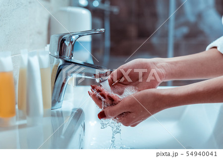 Lady with red manicure washing hands in a sink 54940041