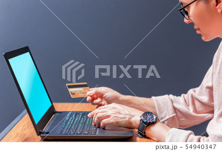man holding credit card and using laptop computer 54940347