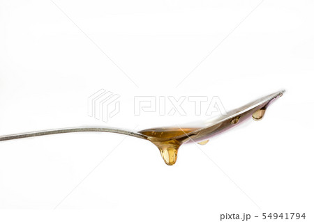 Honey dripping from a silver spoon on isolated white background Honey dripping from a silver spoon on isolated white background 54941794