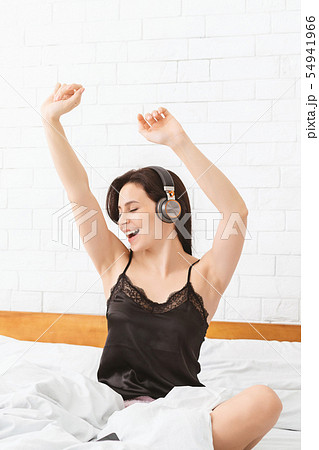 Energetic girl dancing in bed, listening to music 54941966