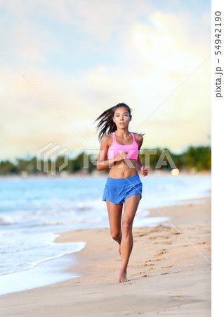 Confident Woman Runner Jogging On Beach Shore 54942190