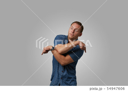 A man in a shirt shows with his hands on your text or your advertisement on a gray background 54947606