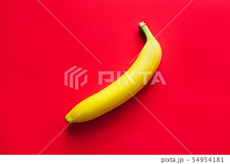 One yellow banana on a red background. 54954181