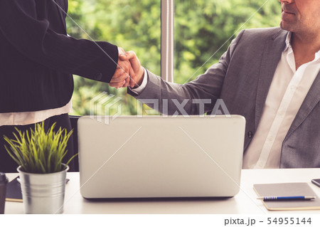 Businessman handshake businesswoman in office. 54955144