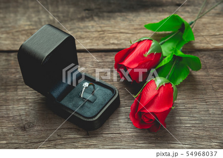 wedding ring and red rose flowers on wood table wedding ring and red rose flowers on wood table 54968037