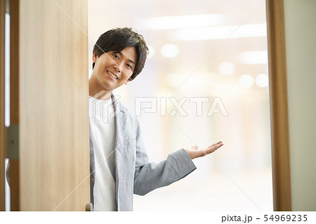 ドアを開けて出迎える20代男性 54969235