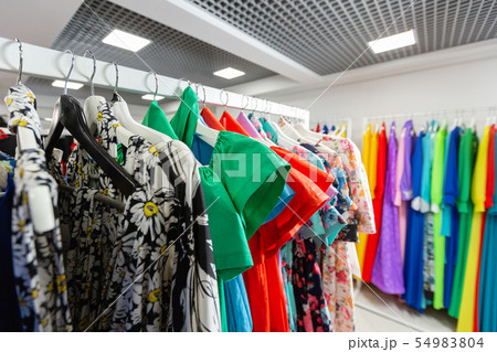 Cocktail dress. Clothing on hanger at the modern shop boutique. Bright multi-colored fabrics Cocktail dress. Clothing on hanger at the modern shop boutique. Bright multi-colored fabrics 54983804