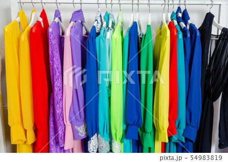Cocktail dress. Clothing on hanger at the modern shop boutique. Bright multi-colored fabrics Cocktail dress. Clothing on hanger at the modern shop boutique. Bright multi-colored fabrics 54983819