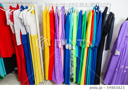 Cocktail dress. Clothing on hanger at the modern shop boutique. Bright multi-colored fabrics Cocktail dress. Clothing on hanger at the modern shop boutique. Bright multi-colored fabrics 54983823