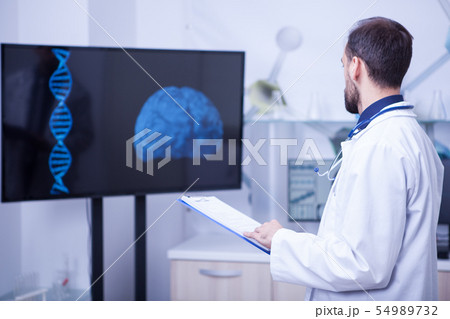 Doctor in his cabinet looking at a braind and trying to put a diagnosis Doctor in his cabinet looking at a braind and trying to put a diagnosis 54989732