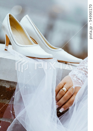 wedding shoes with heels are hanging on a white 54990170