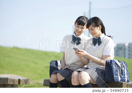 スマートフォンを見ている女子校生2人 スマートフォンを見ている女子校生2人 54990715
