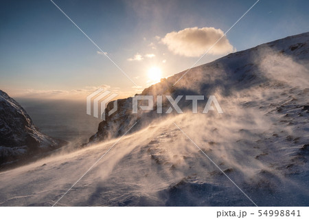 Sunset on snowy hill in blizzard at sunset Sunset on snowy hill in blizzard at sunset 54998841