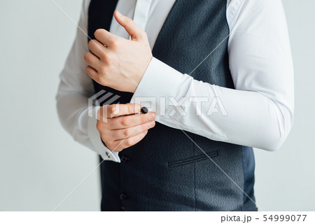 Close-up of a man in a tux fixing his vintage cufflink. groom bow tie cufflinks Close-up of a man in a tux fixing his vintage cufflink. groom bow tie cufflinks 54999077