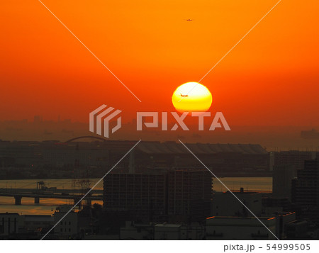 羽田空港 夕日を横切る飛行機 / a airplane flying in front of th 羽田空港 夕日を横切る飛行機 / a airplane flying in front of th 54999505