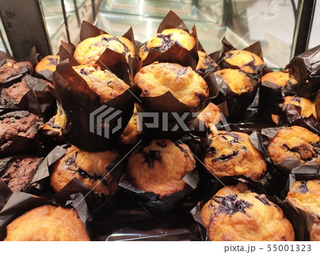 Various types of muffins are displayed for sale. 55001323