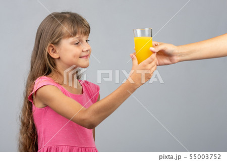 The girl takes from her hand a glass of orange The girl takes from her hand a glass of orange 55003752