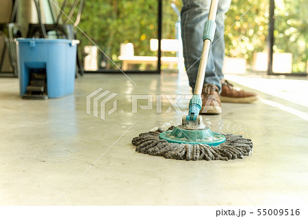 Man worker with mop and bucket cleaning floor in the cafe. 55009516