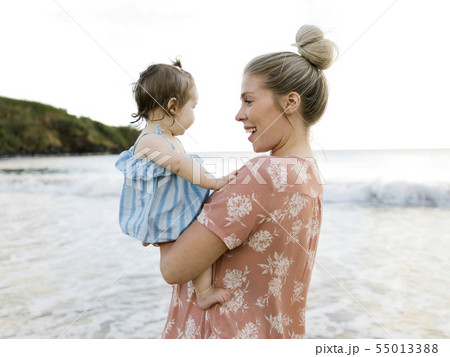 Woman holding baby daughter on beach 55013388