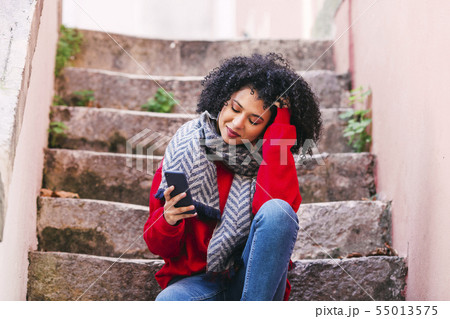 Young woman with smart phone sitting on steps 55013575